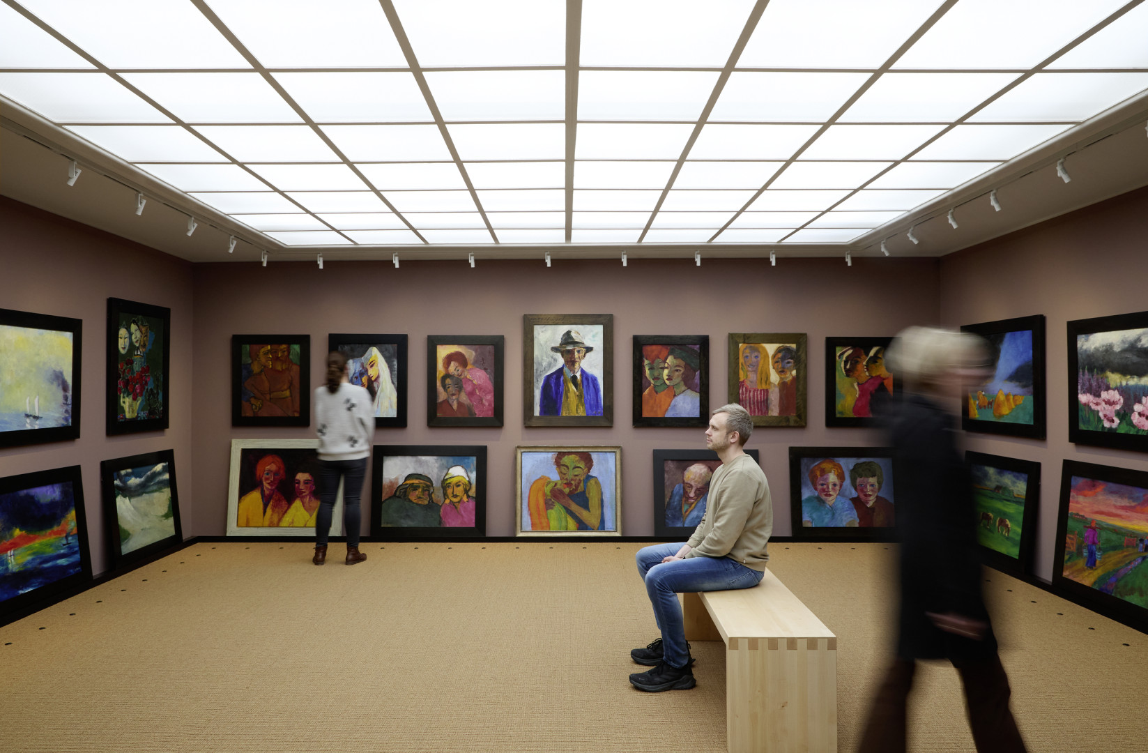 Tre besøgende betragter malerier af Emil Nolde i billedsalen i Nolde-huset.