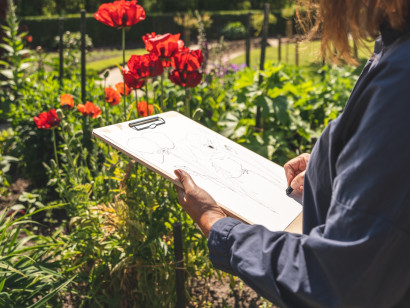 Person in the Nolde Garden with a sketchpad, creating a drawing.